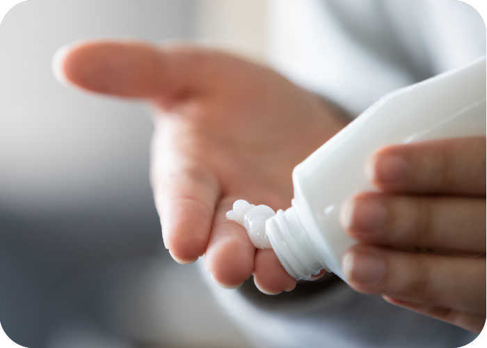 Eine Person drückt Creme aus einer Tube auf die Hand 