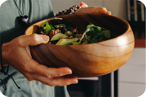 Eine Person hält eine große Holzschüssel mit frischem Salat.